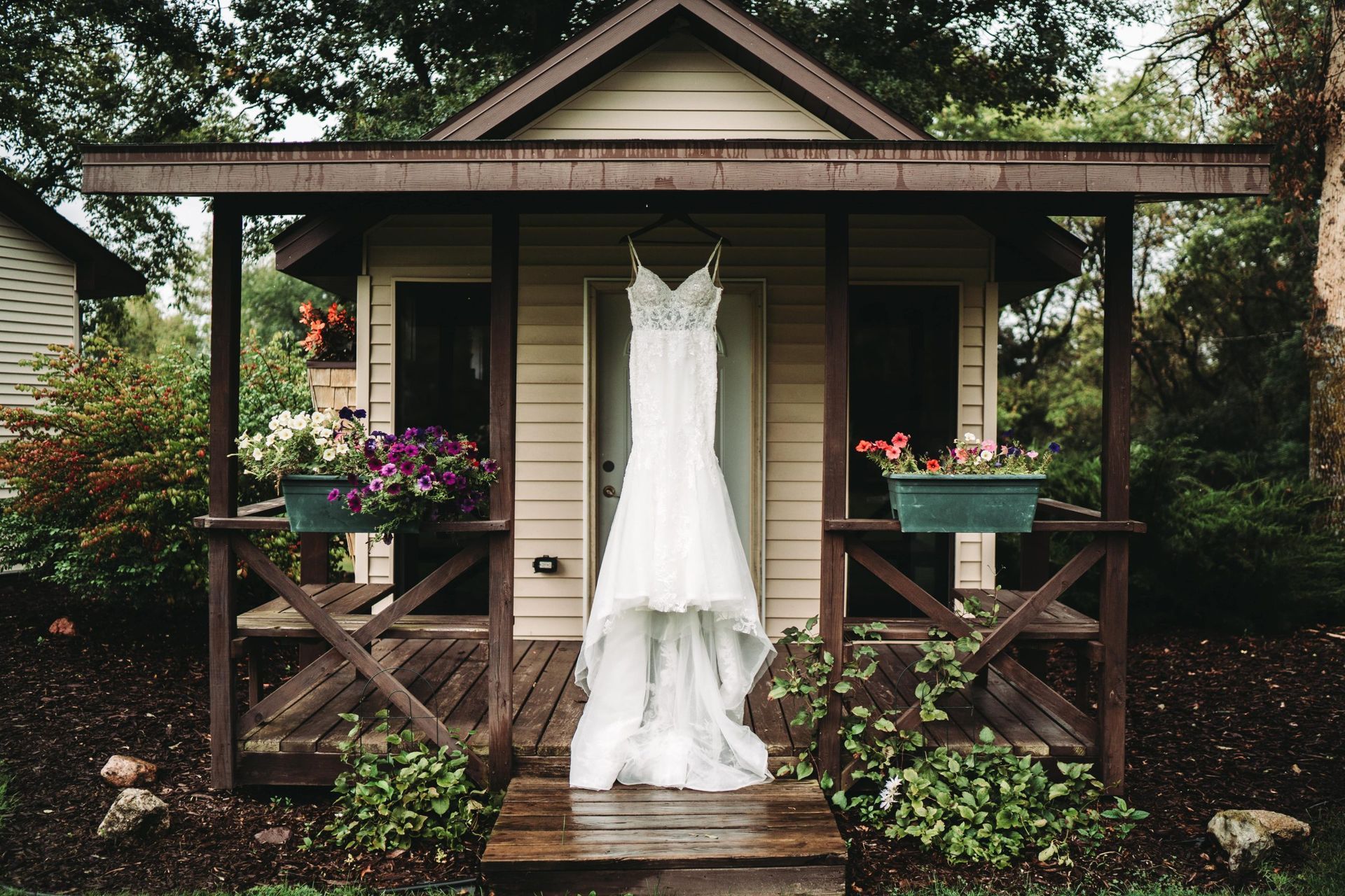 Wedding dress hanging on a small wooden porch with flower boxes.