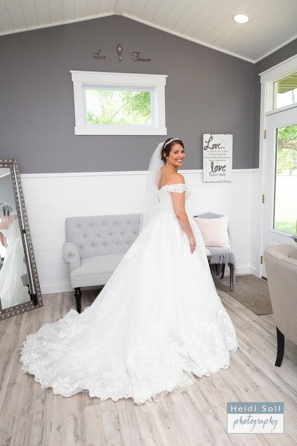 Bride in white wedding dress, smiling, in a gray and white room.