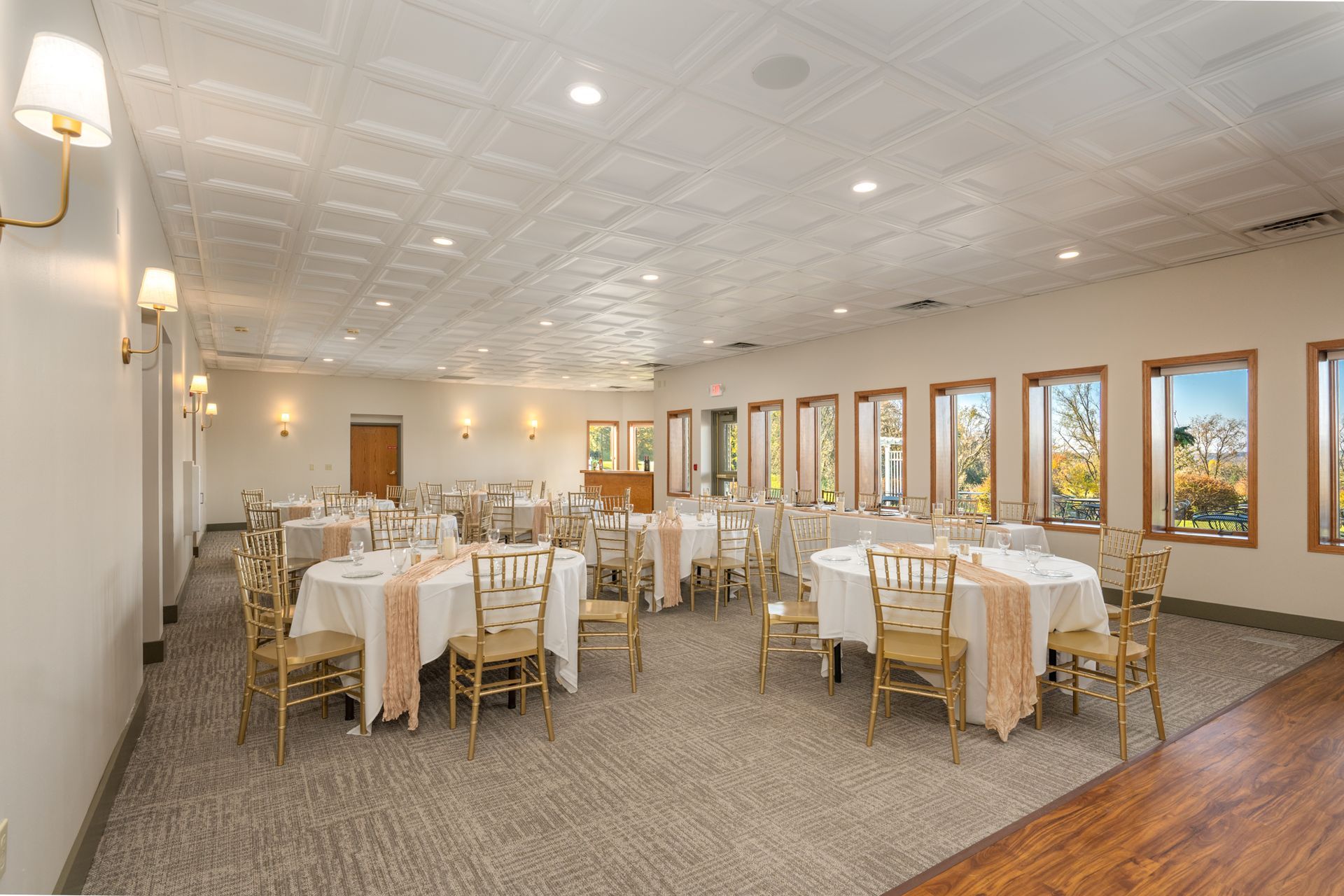 Formal dining room with round tables set with white linens and blush-colored runners.