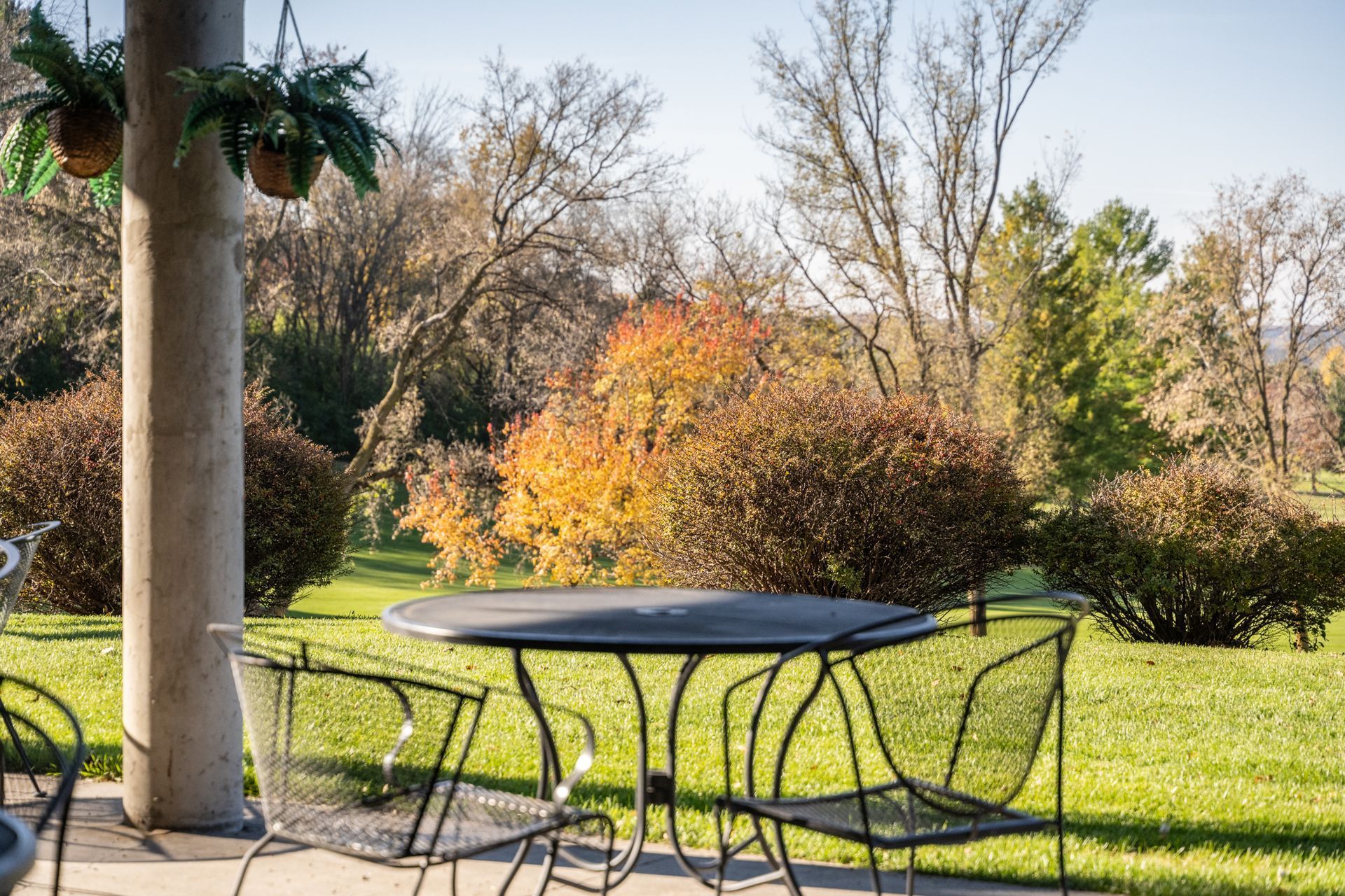 Outdoor patio with black metal furniture, overlooking fall foliage.