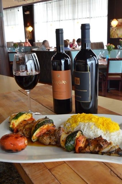 Two bottles of wine and a plate of food on a table