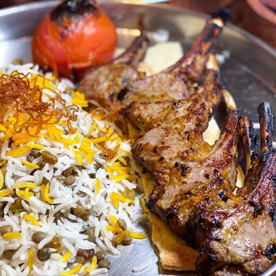 A close up of a plate of food with meat and rice on a table.
