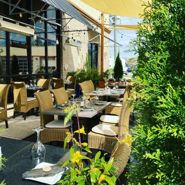 A restaurant patio with tables and chairs under an umbrella