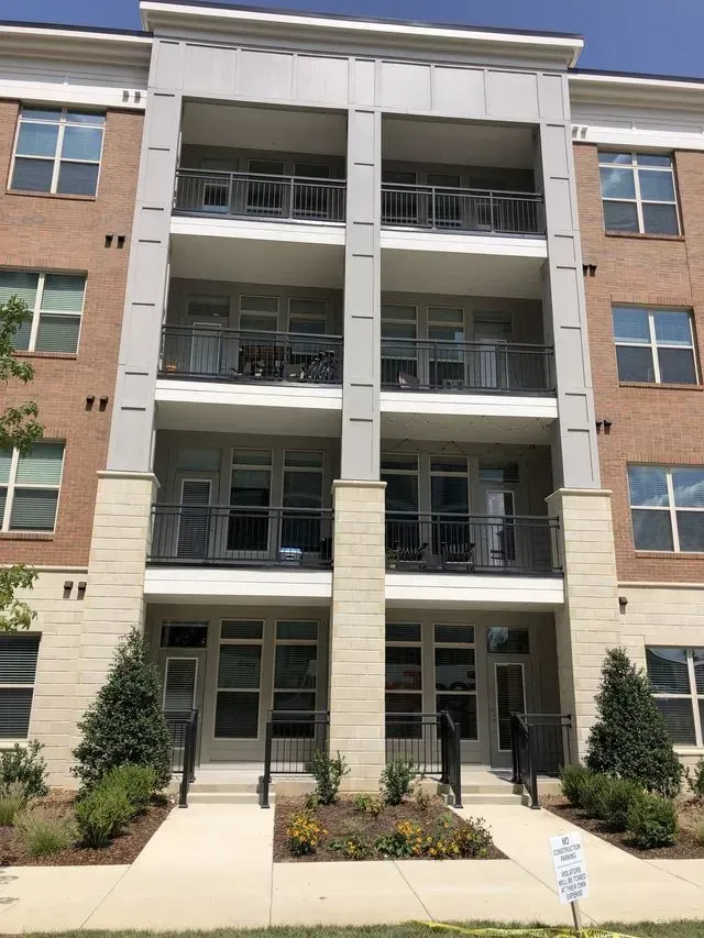Apartment building with three-story balconies, brick and light-colored stone facade.
