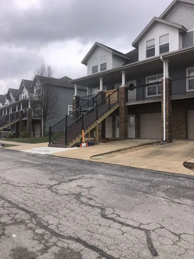 Row of multi-story townhouses with stairs leading up to the front doors and garage doors below.