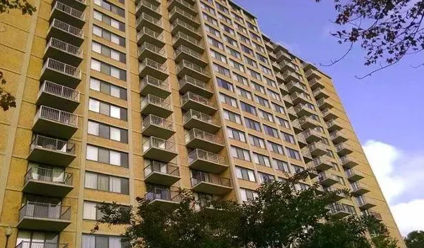 A tall beige apartment building with many balconies against a blue sky.