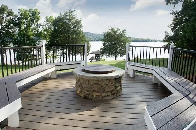 Deck overlooking a lake, with stone fire pit and built-in benches.