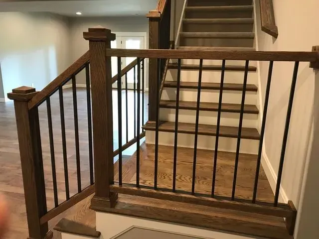 Wooden staircase with black metal balusters and oak handrail.