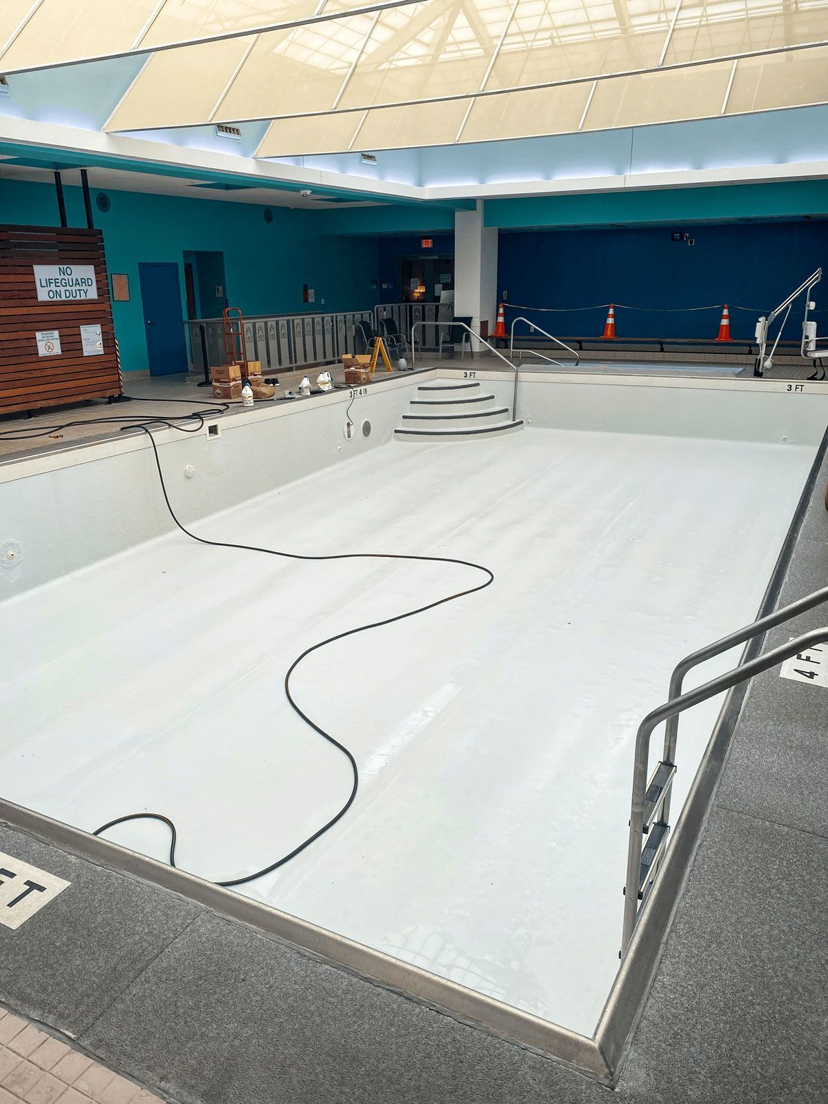 An empty swimming pool is being remodeled in a building.