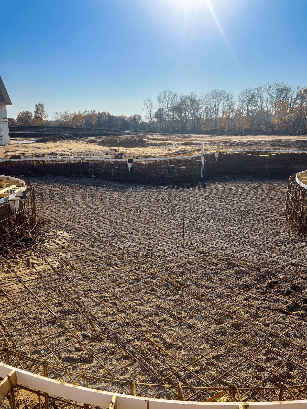 A dirt field with a fence around it and a white building in the background.