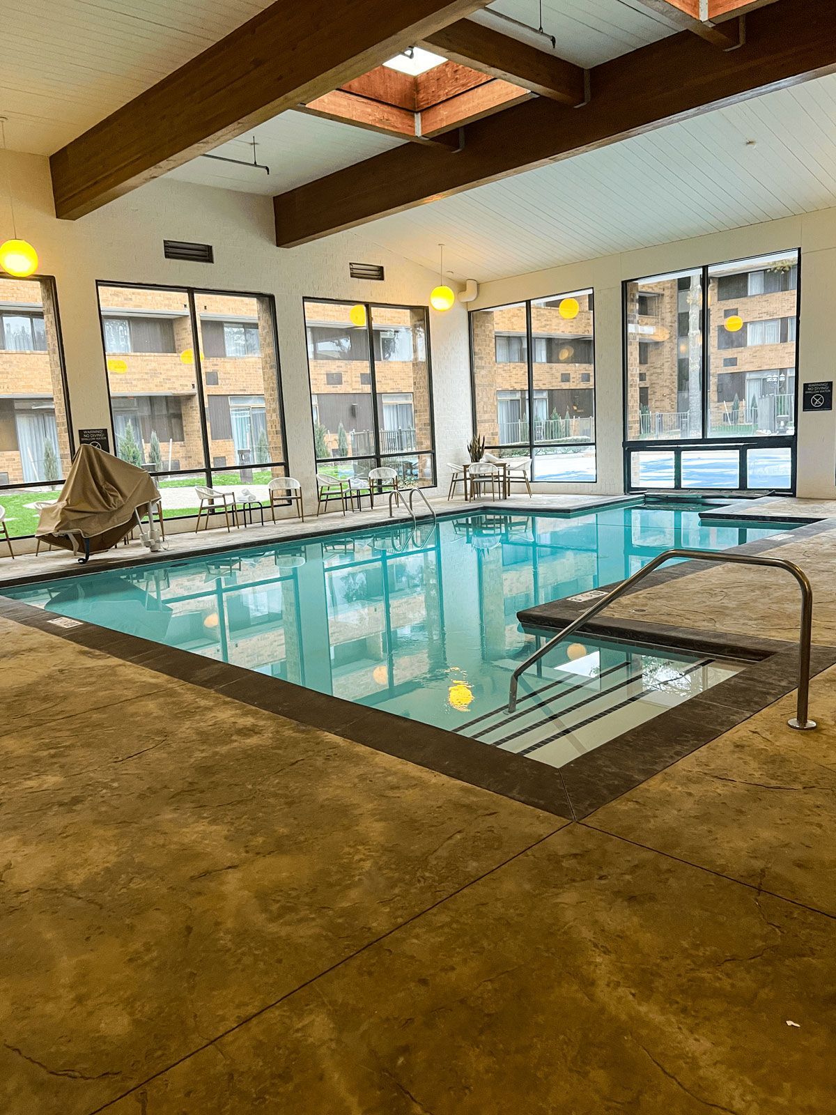 There is a large indoor swimming pool with a lot of windows.