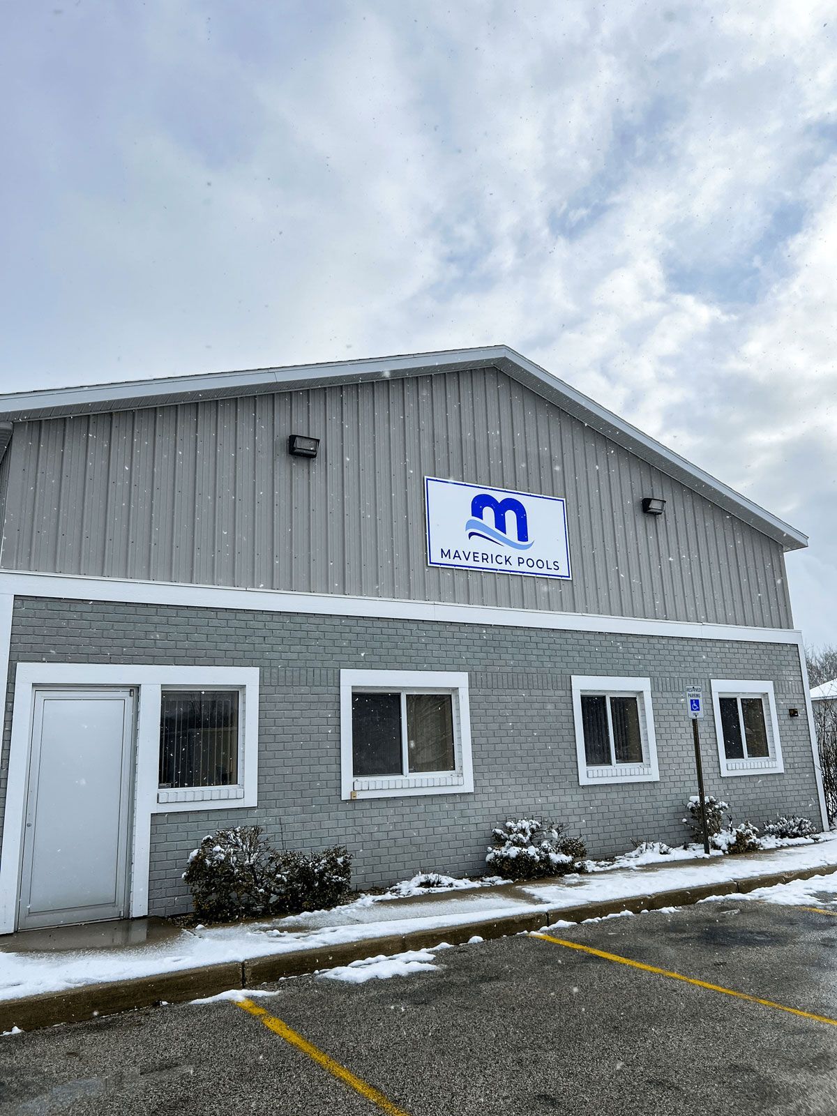 A large brick building with a sign on the side of it and a parking lot in front of it.