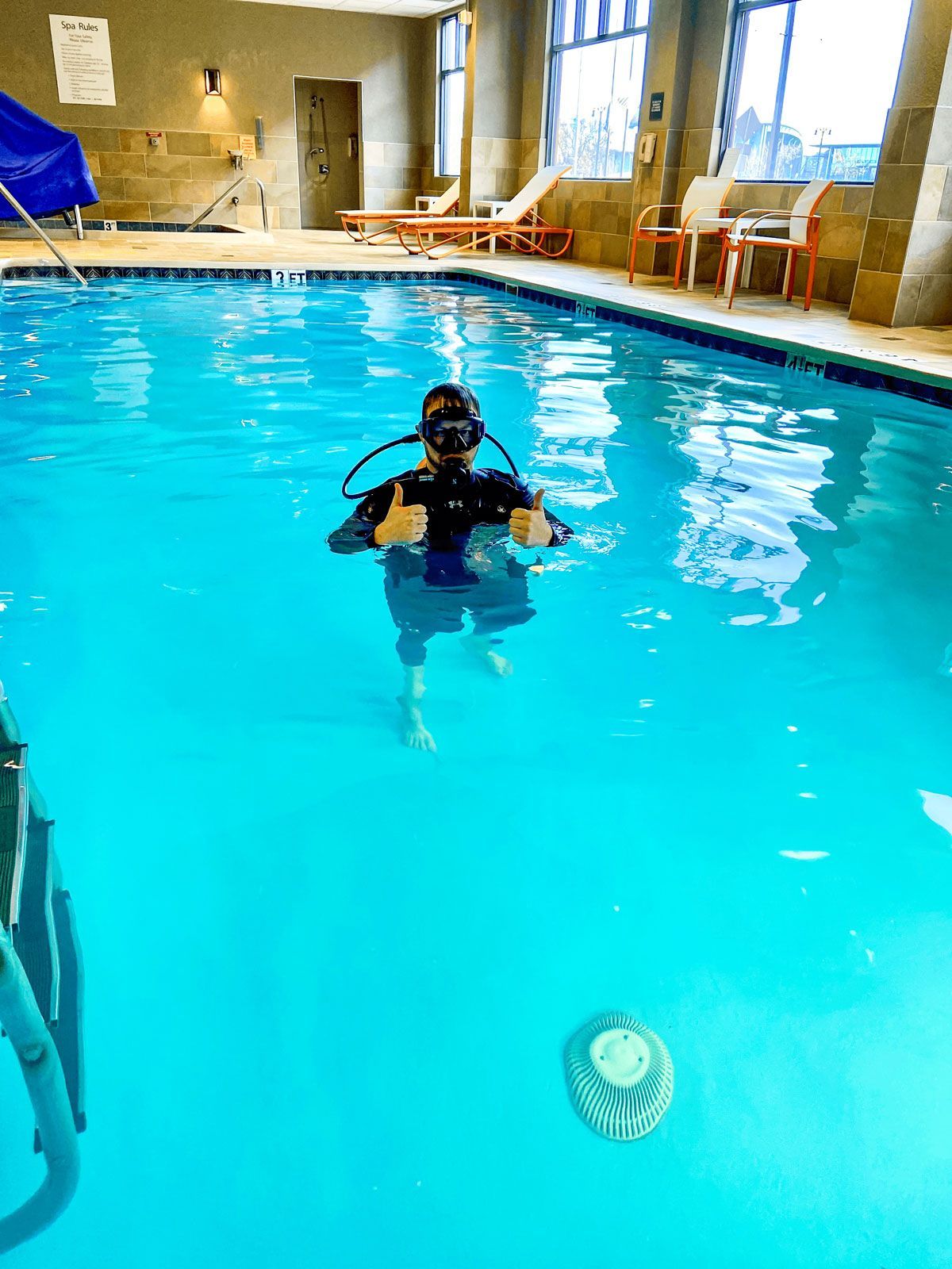 A scuba diver is giving a thumbs up in a swimming pool.