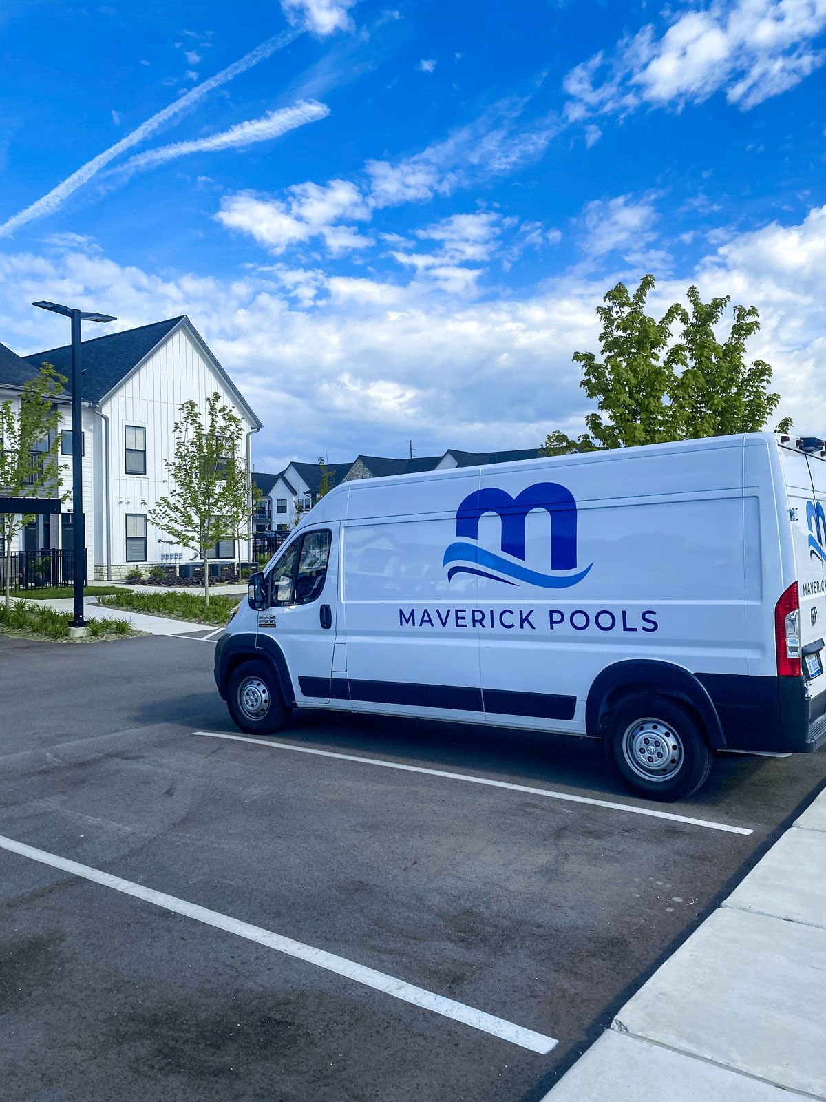 A maverick pools van is parked in a parking lot.