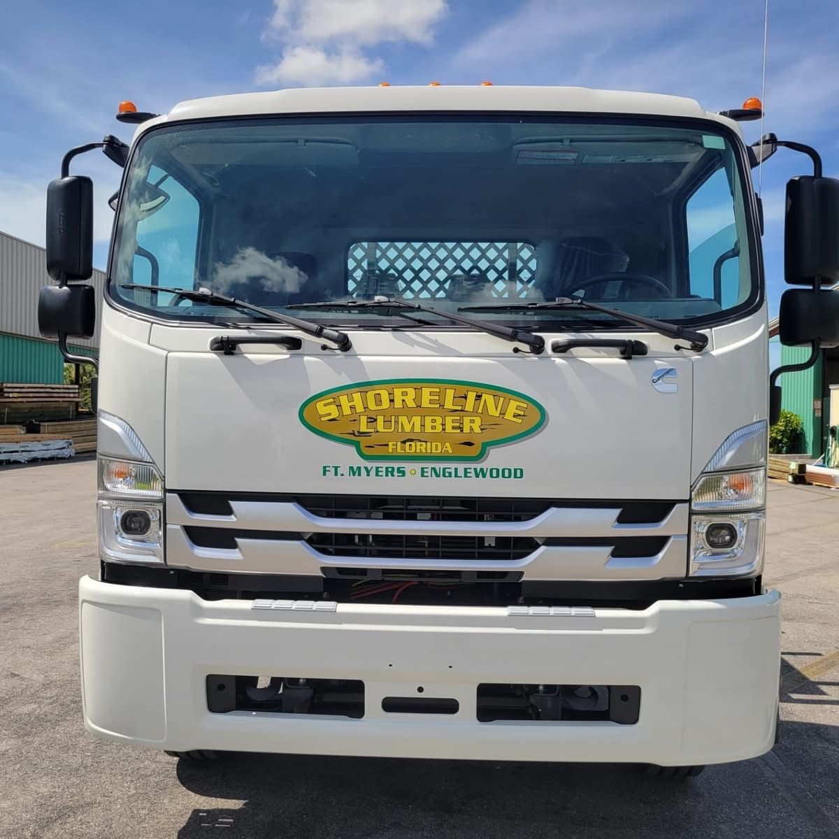 A white shoreline lumber truck is parked in a parking lot
