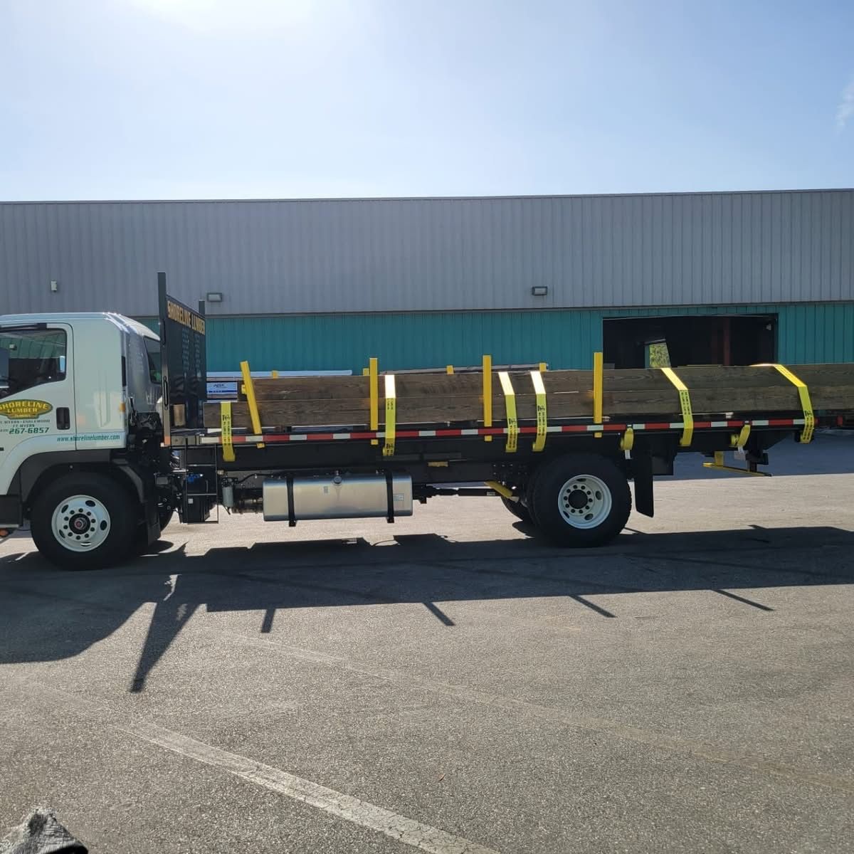 A flatbed truck is parked in front of a building