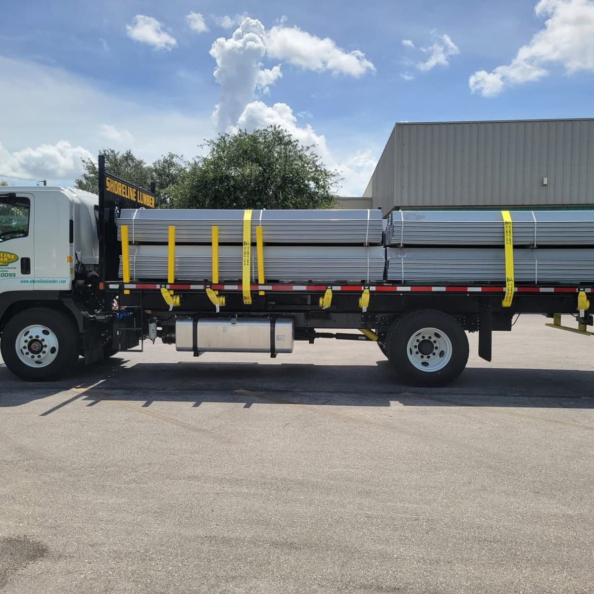 A truck loaded with pipes is parked in a parking lot