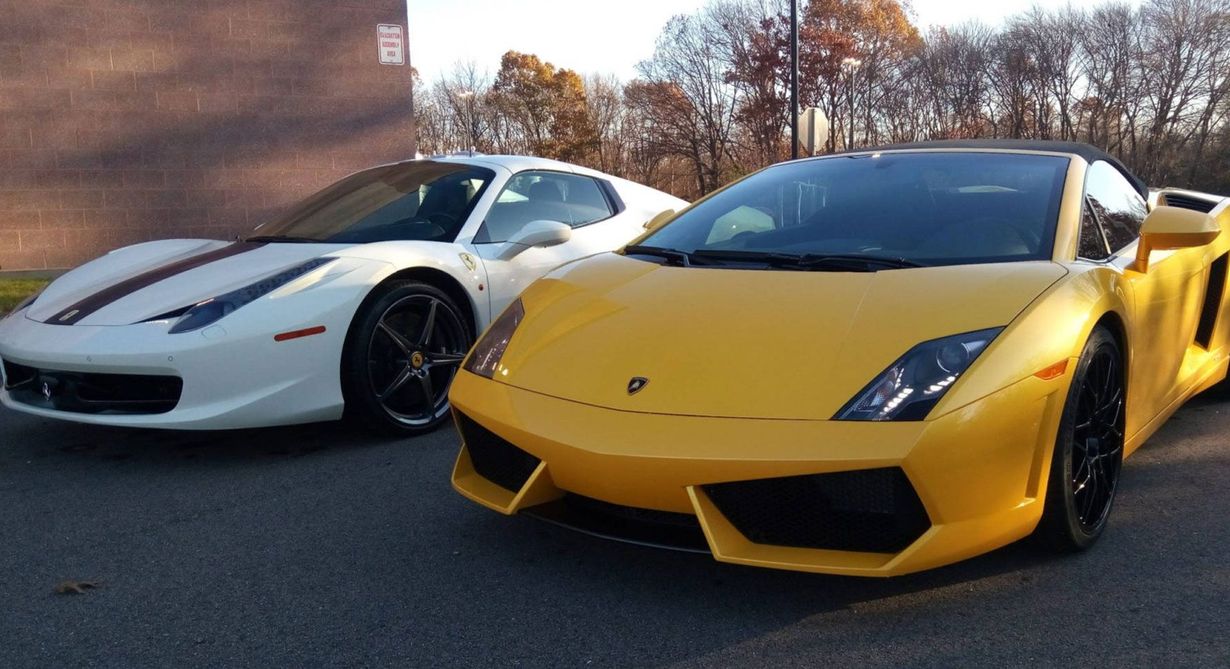 Yellow and white sports cars parked side by side outdoors in front of a brick building.