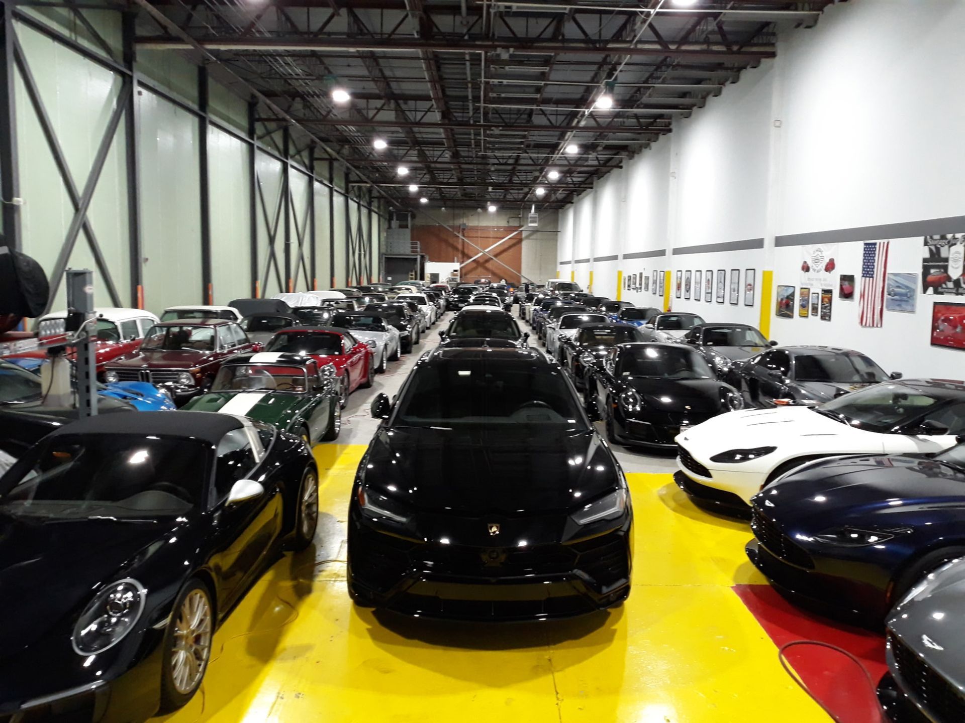 Indoor auto auction showroom filled with rows of exotic sports cars under bright lights