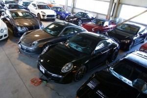 Indoor parking lot filled with parked cars, mostly black and silver sports sedans.