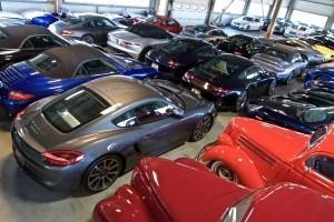 Rows of sports cars in a showroom, including red, blue, gray, and black vehicles.