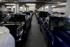 Indoor parking garage with several parked cars, including a black sports car and blue vehicle in foreground