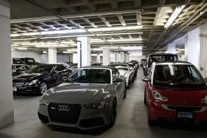 Indoor parking garage with several cars, including a silver Audi and a red Smart car.