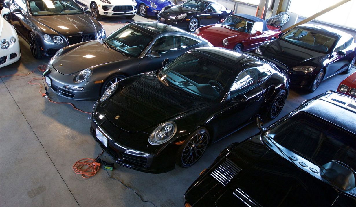 Several black sports cars parked closely in an indoor showroom or garage.