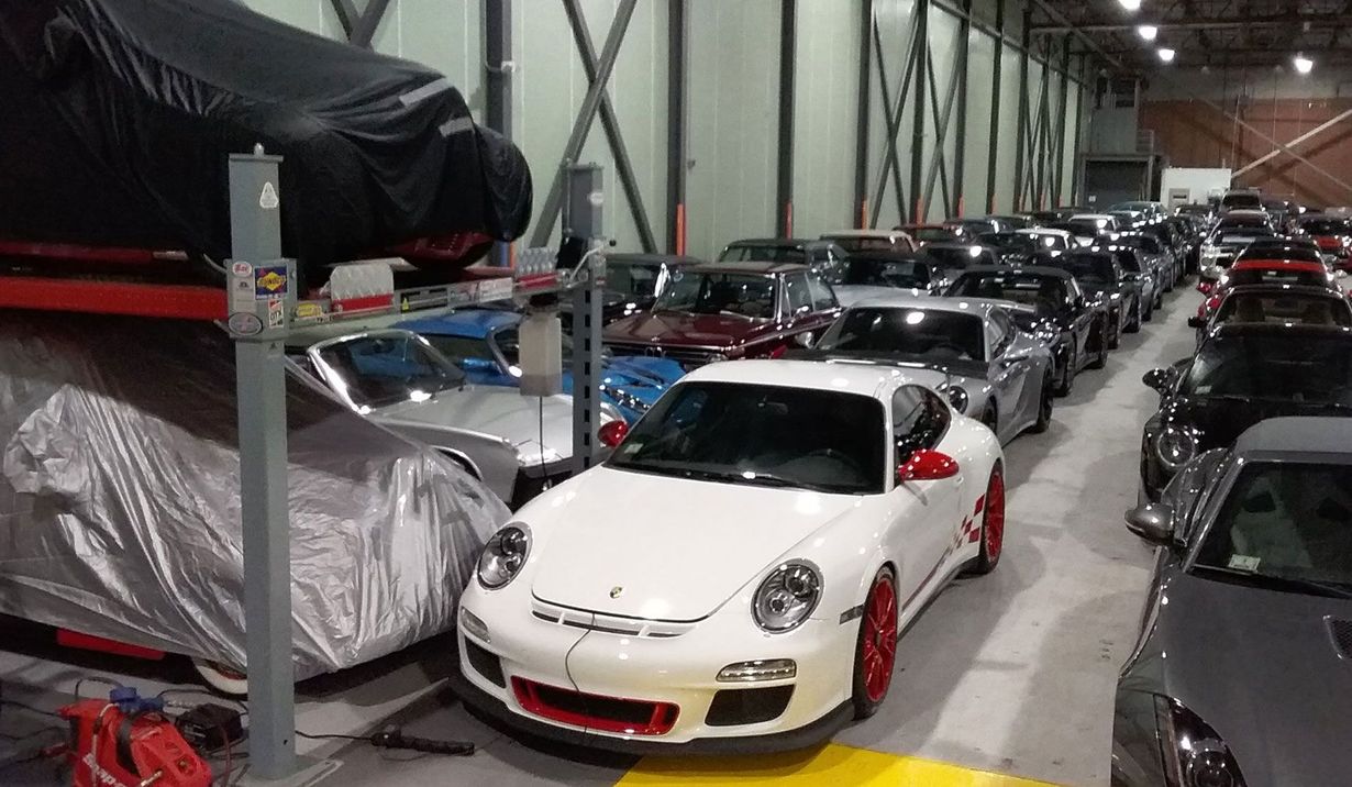 Rows of sports cars in a parking garage, with a white Porsche in the foreground.