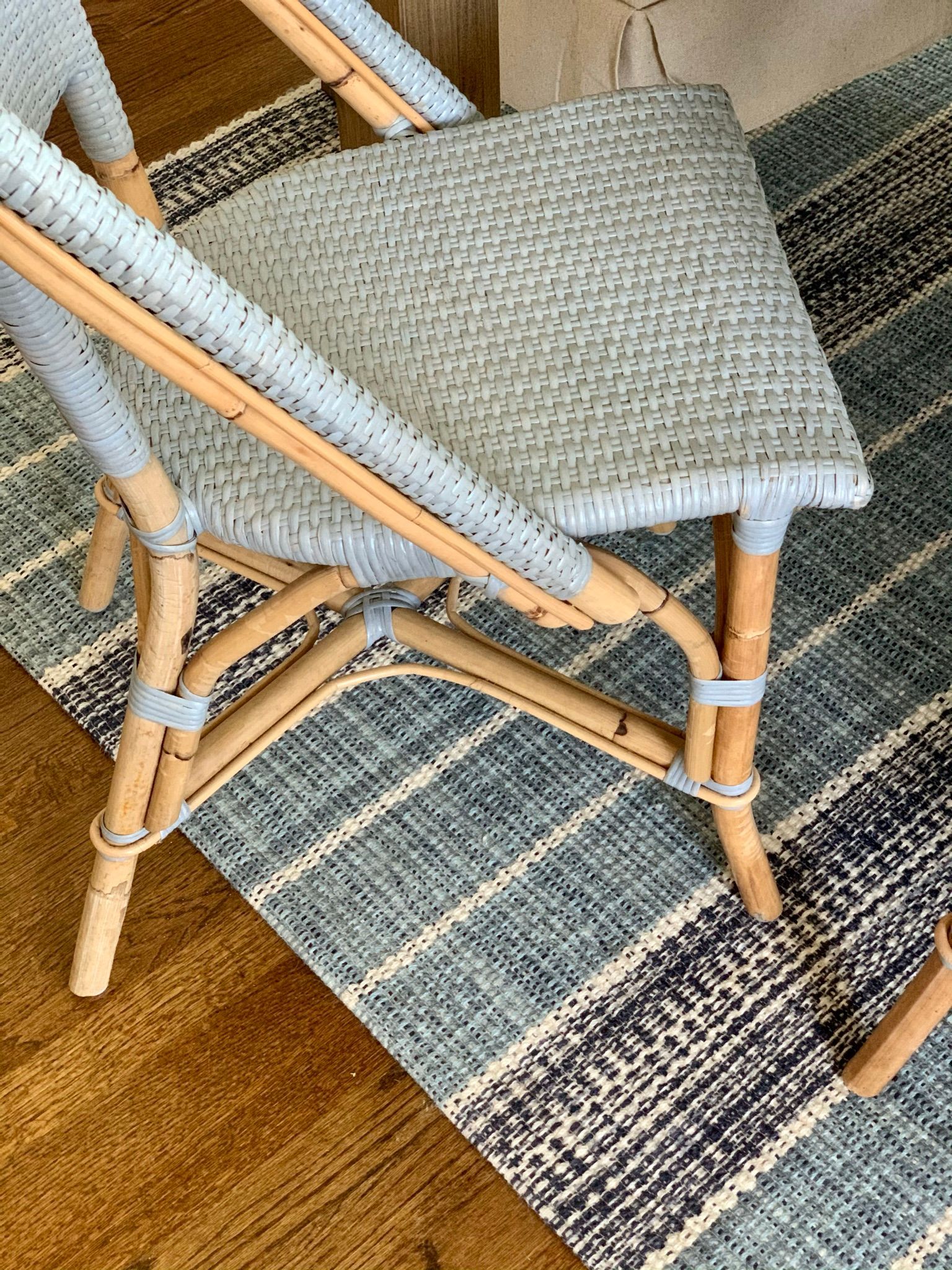 Blue wicker chair on a patterned blue rug and wood floor.