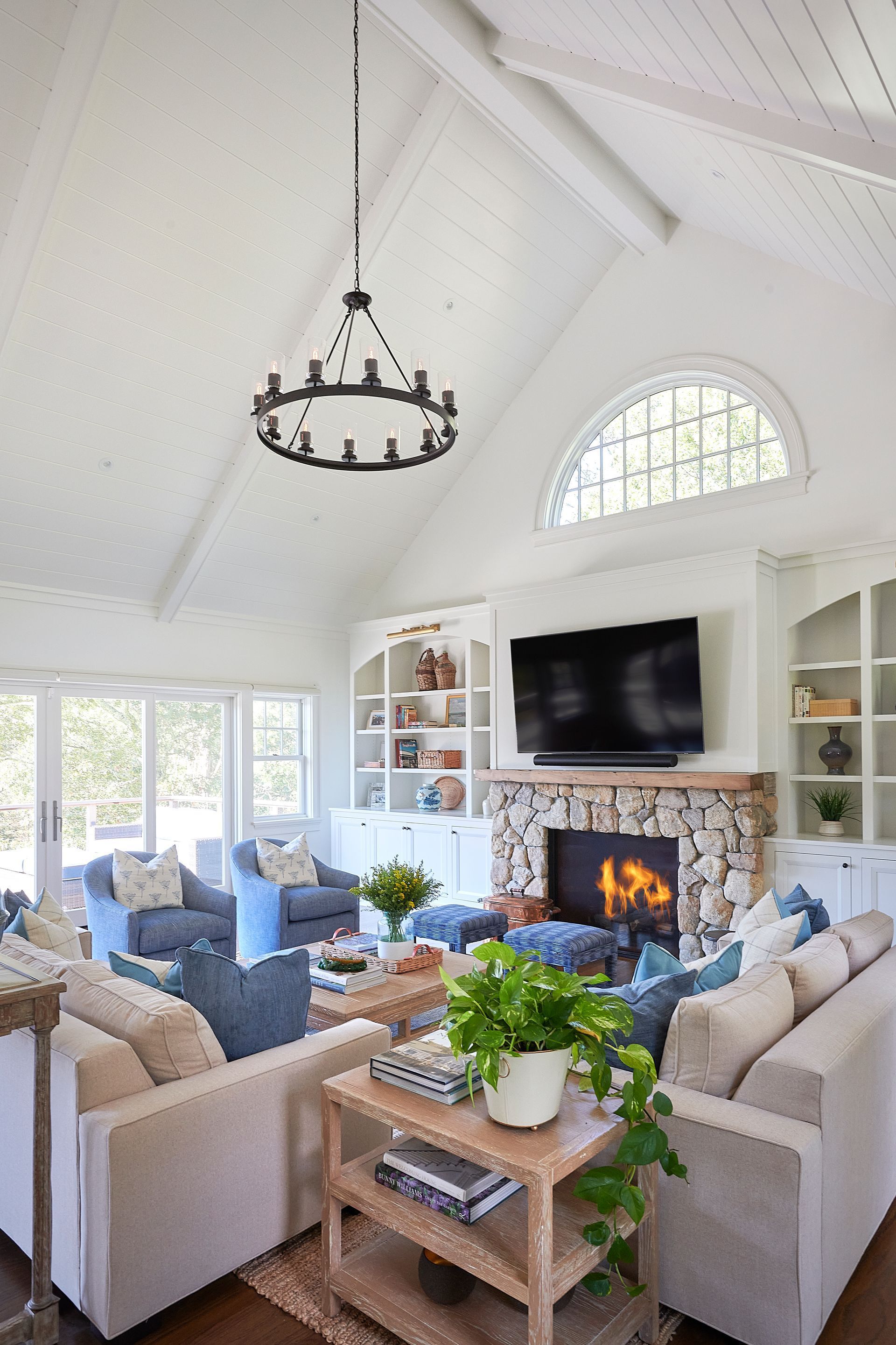 Living room with white walls, fireplace, blue furniture, and chandelier.