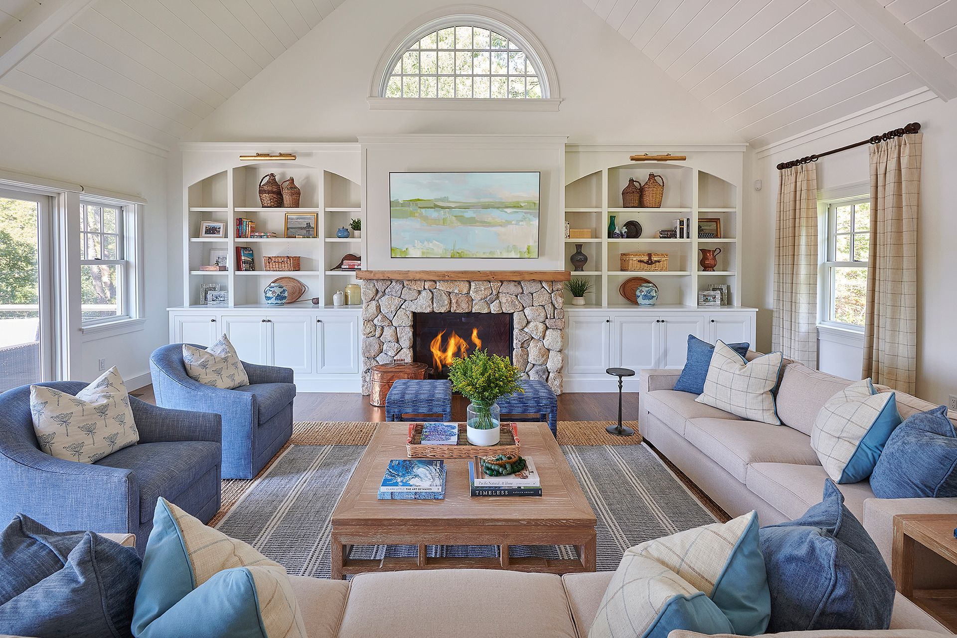 Living room with fireplace, built-in shelves, blue and beige furniture, rug, and arched window.