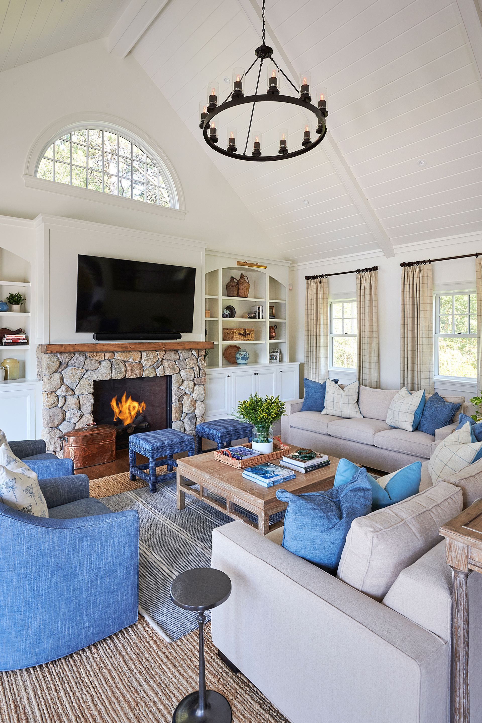 Cozy living room with stone fireplace, white walls, and blue and tan furnishings.