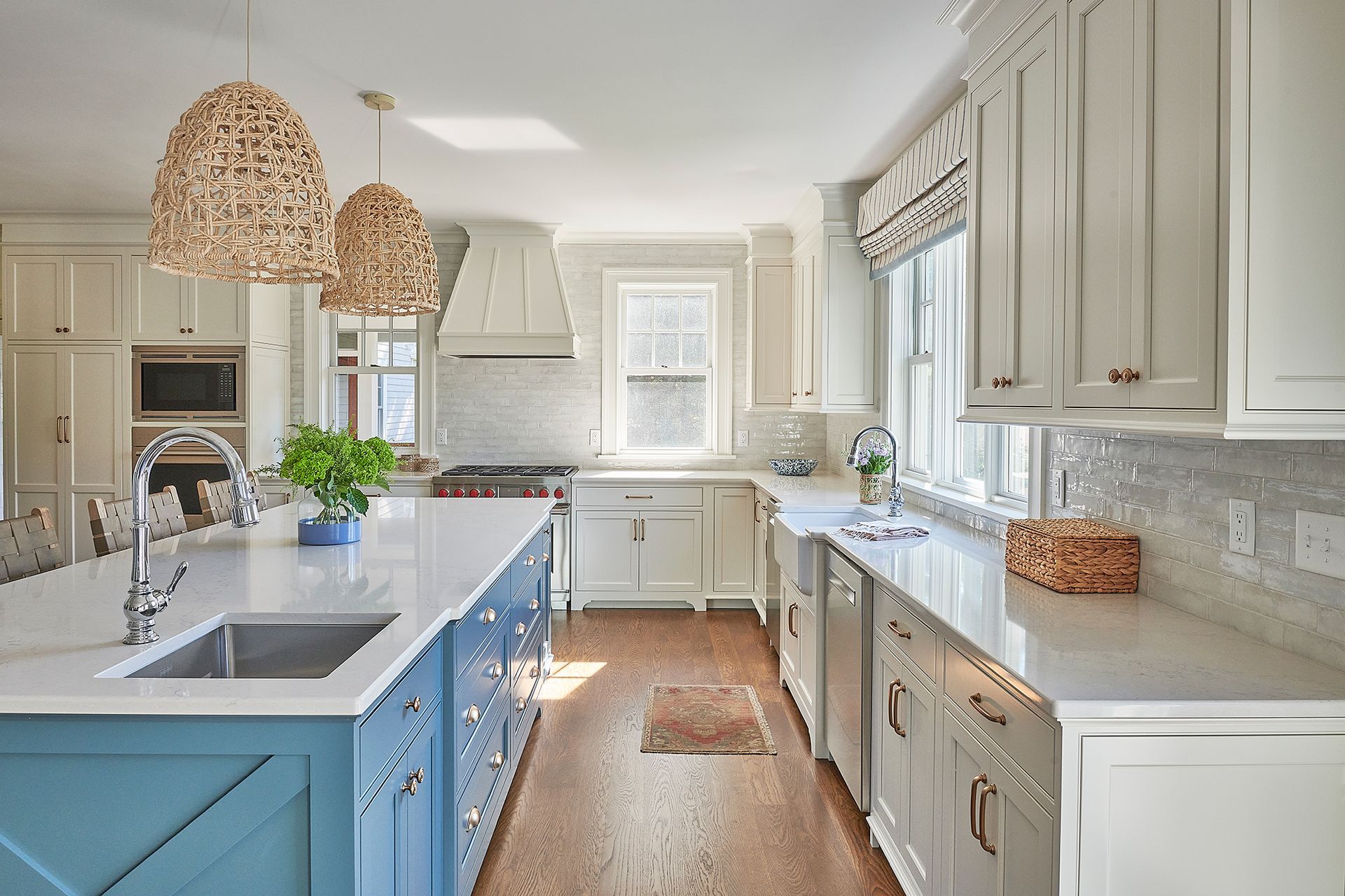 Spacious white and blue kitchen with an island and two woven pendant lights.