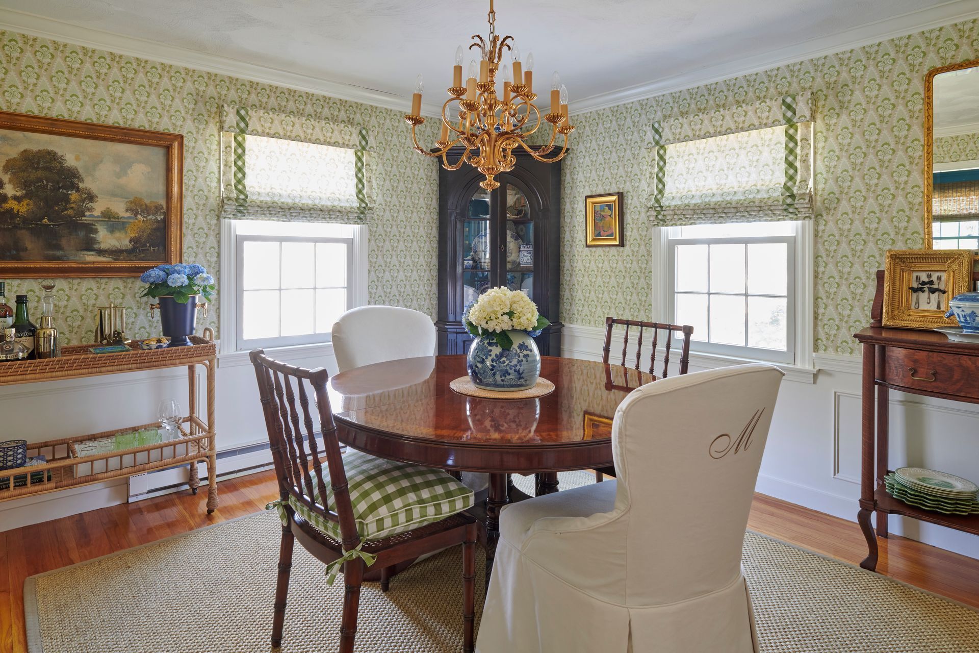 Dining room with round wood table, chairs, chandelier, and patterned wallpaper.