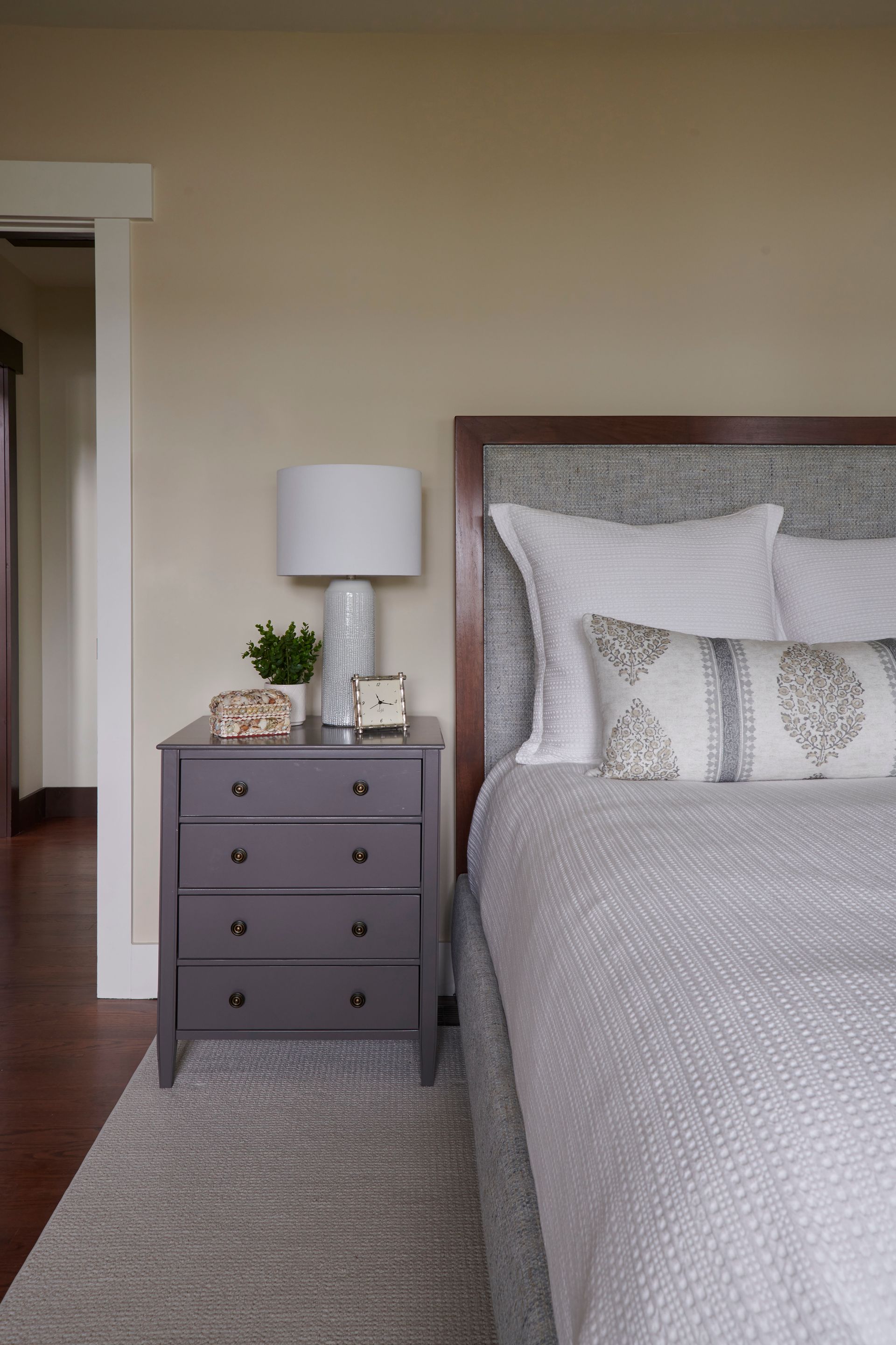 A bedroom with a bed, nightstand, lamp, and dresser