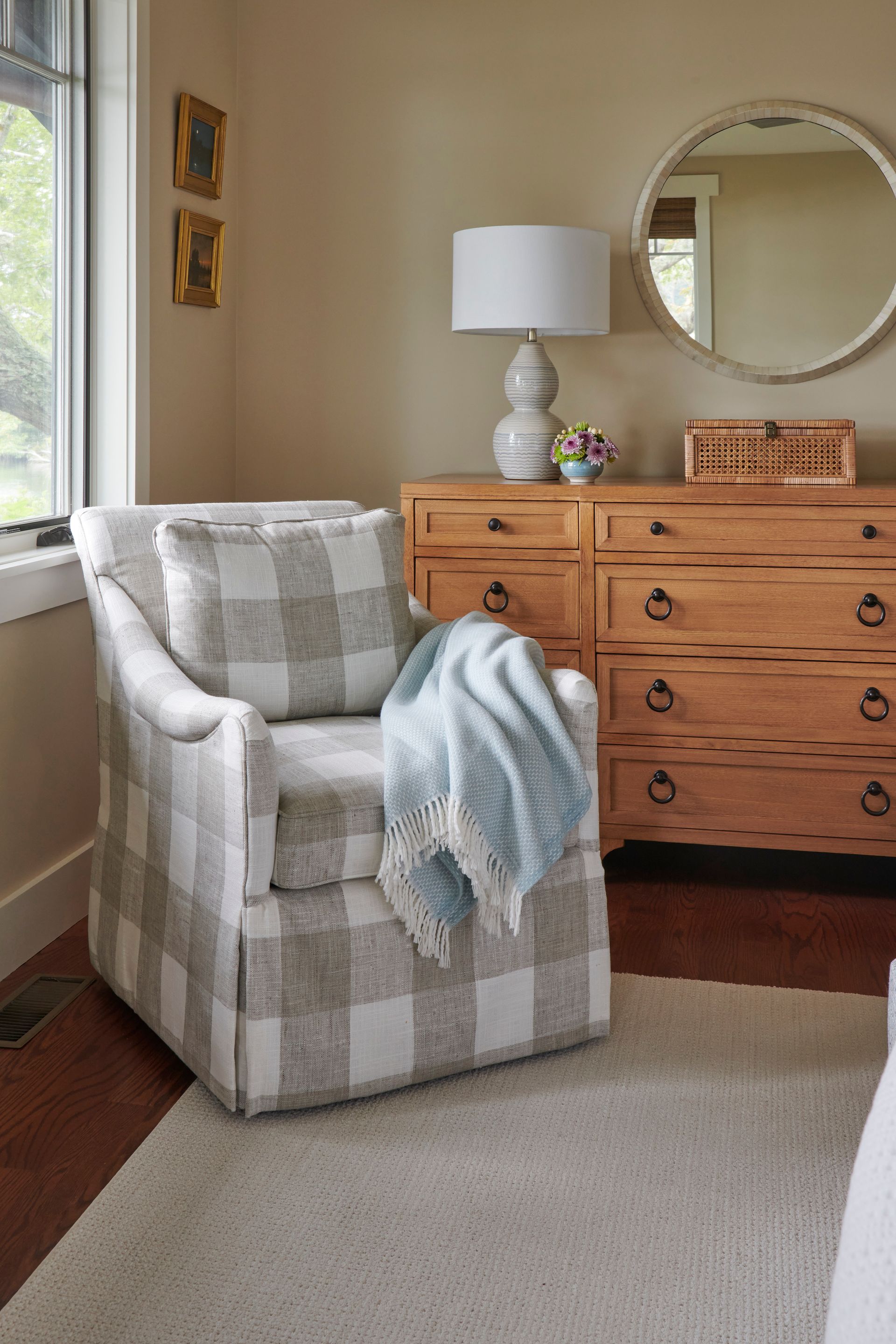 A chair with a blanket on it is sitting in a bedroom next to a dresser