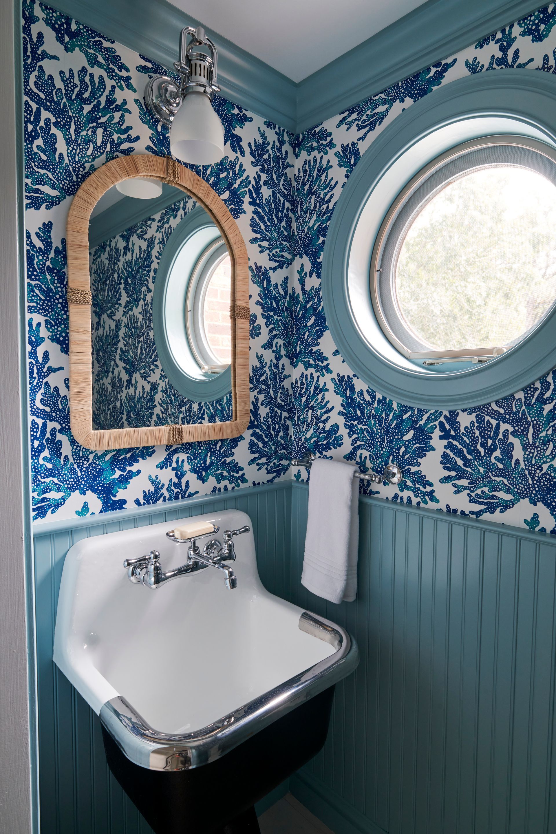 Bathroom with a sink, mirror, and blue and white wallpaper