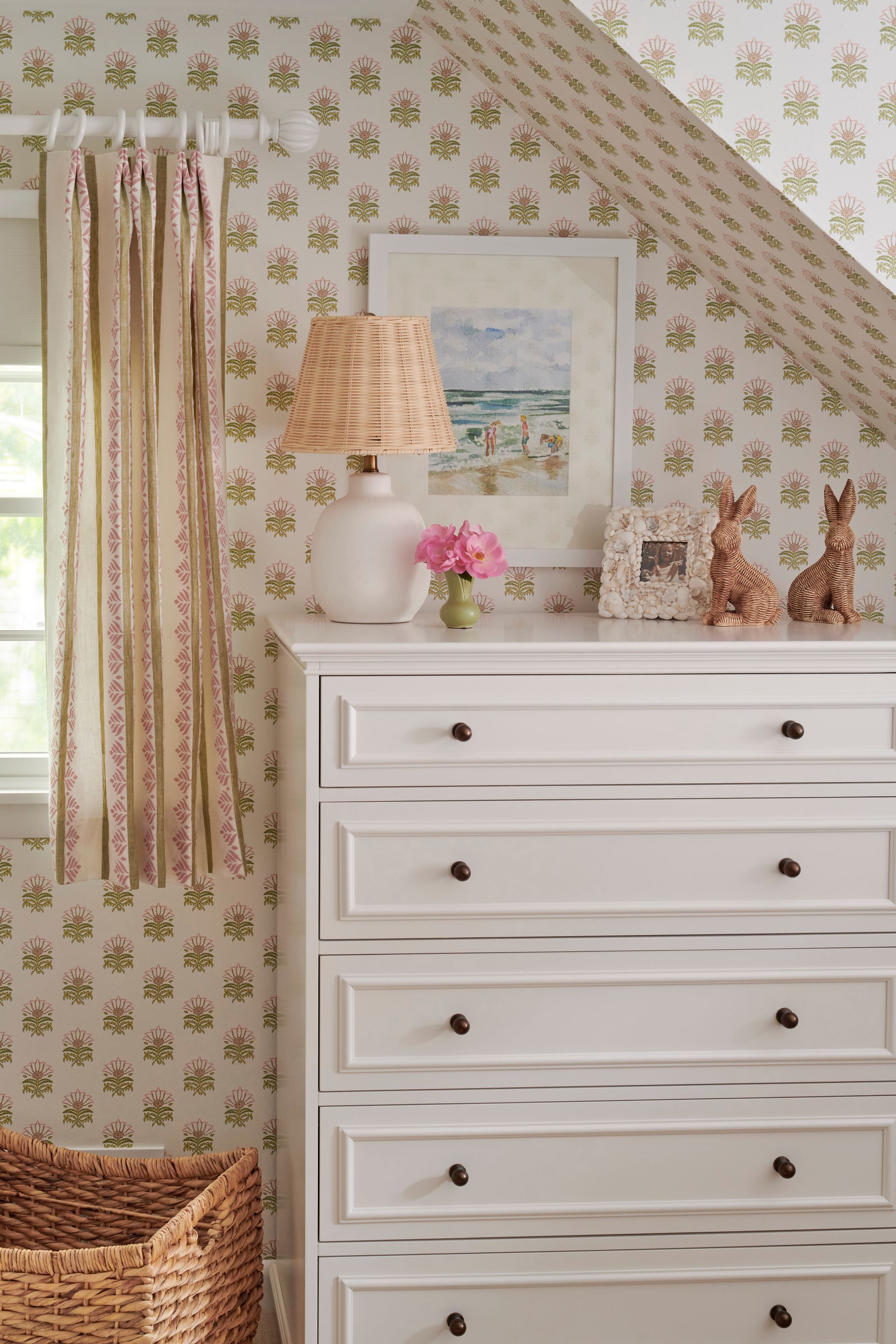 A white dresser with a lamp on top of it in a room with a slanted ceiling