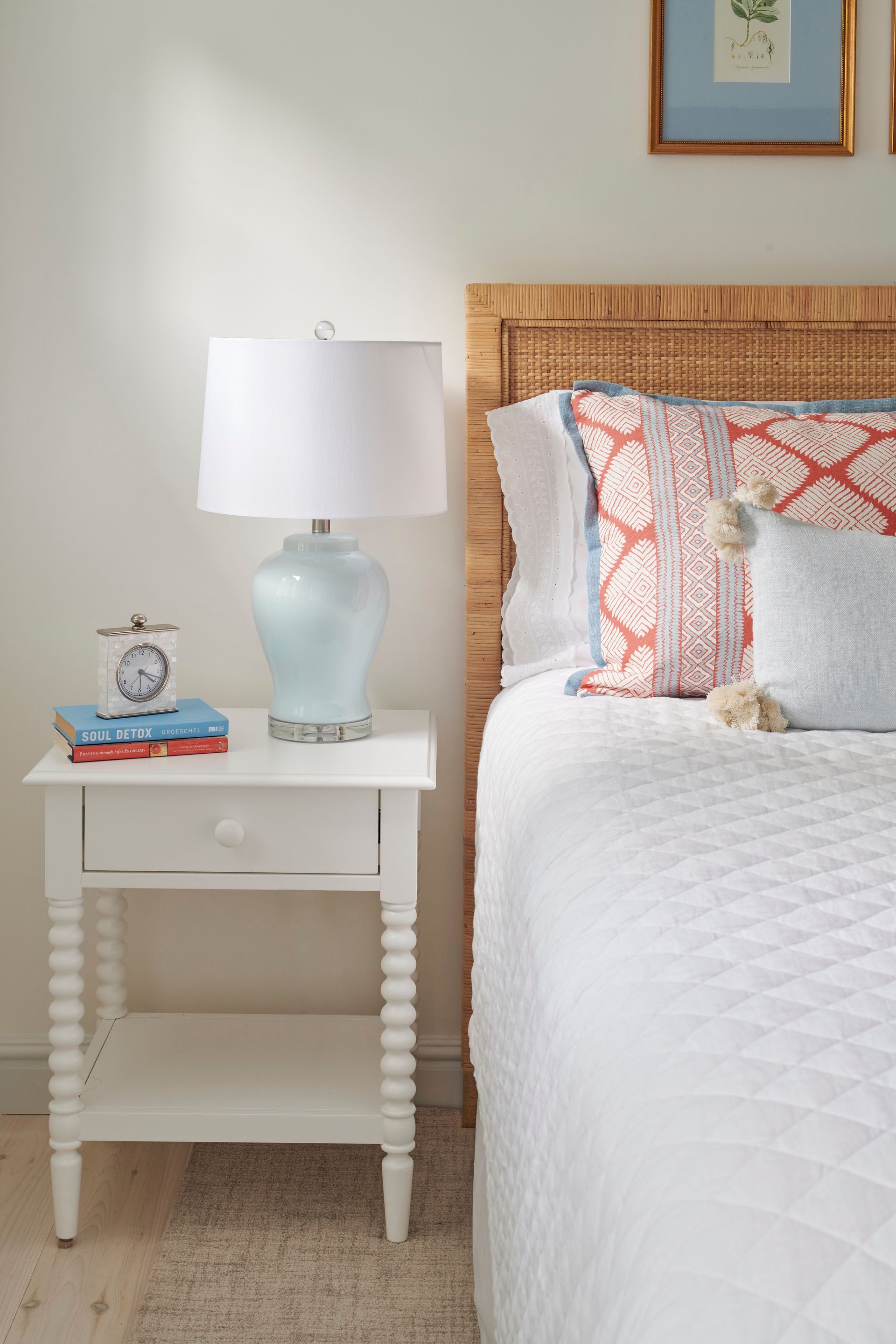 A bedroom with a bed, nightstand, lamp, and wicker headboard