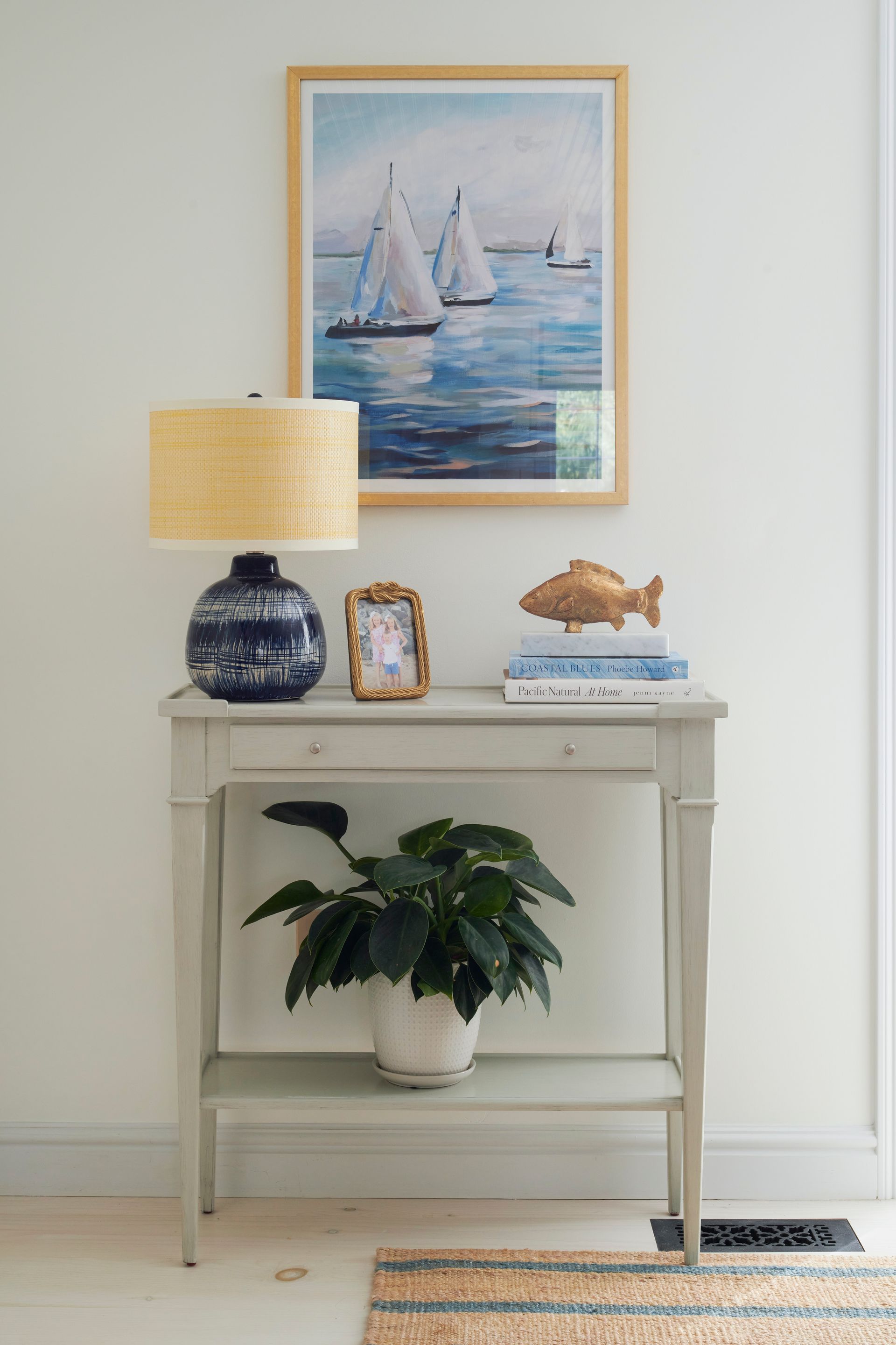 A table with a plant, a lamp, and a painting on the wall
