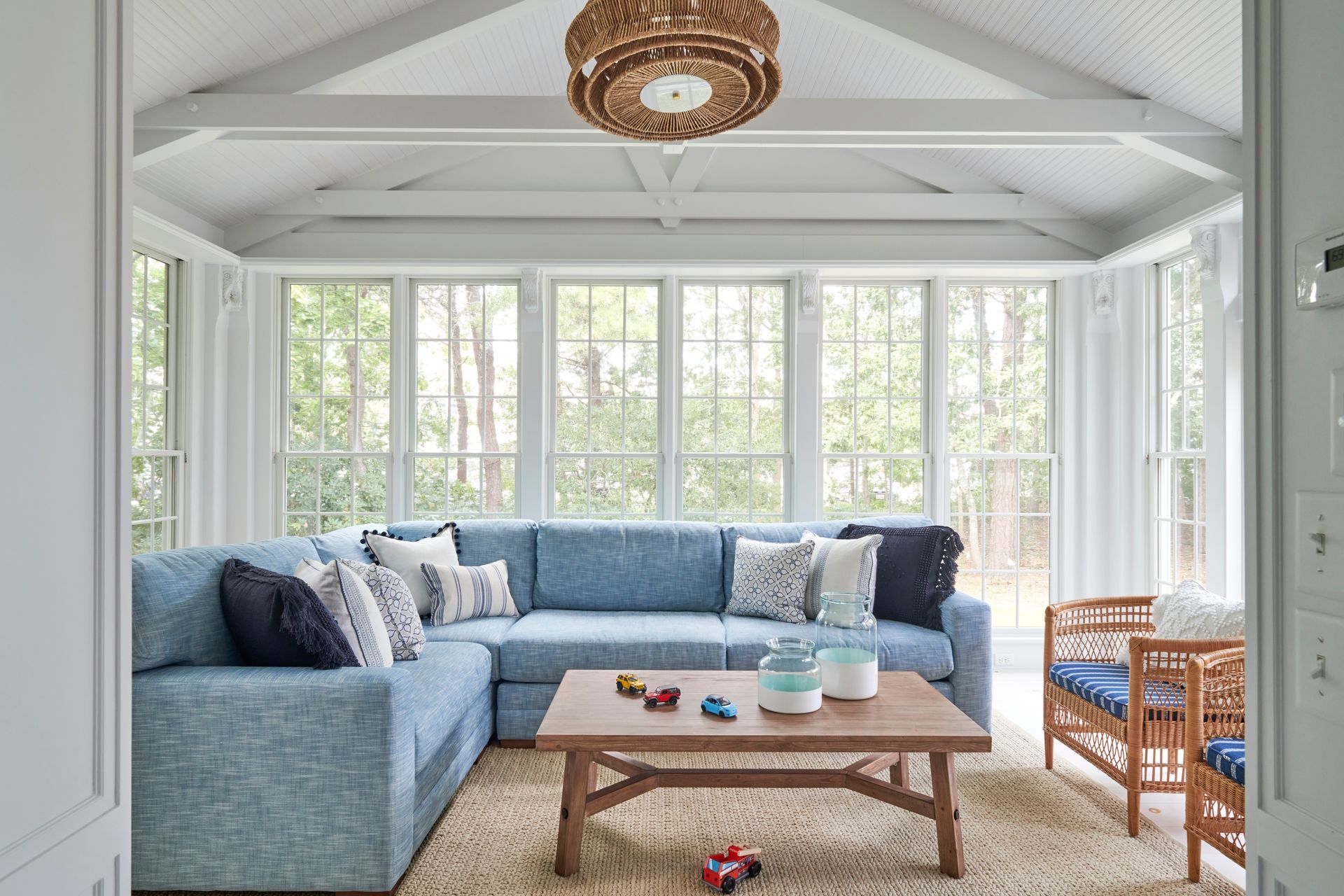 A sunroom with a blue sectional couch and a wooden coffee table