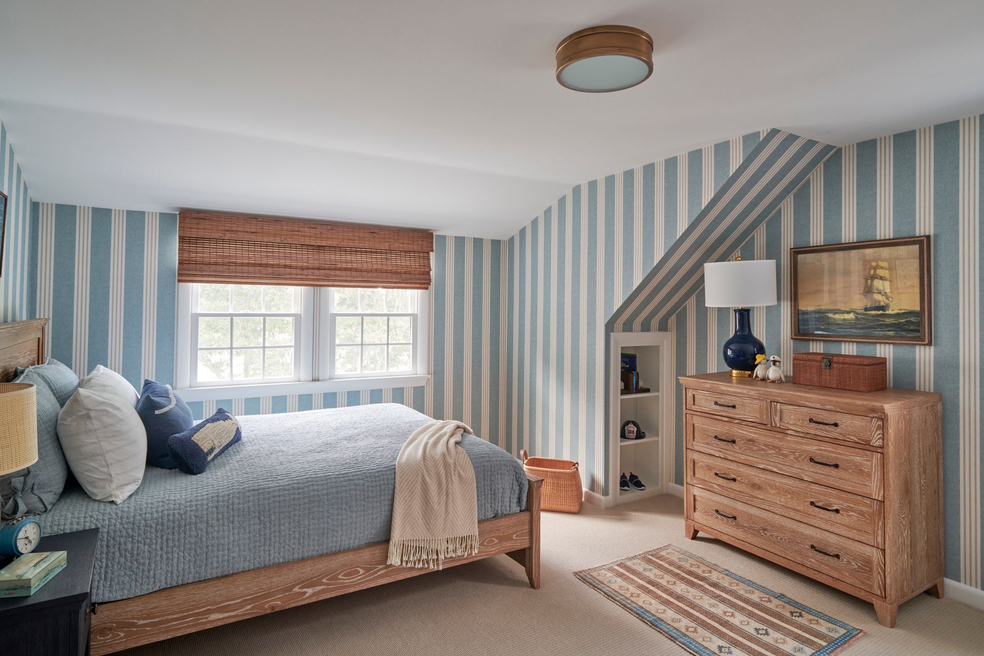 A bedroom with a bed, dresser, and striped walls