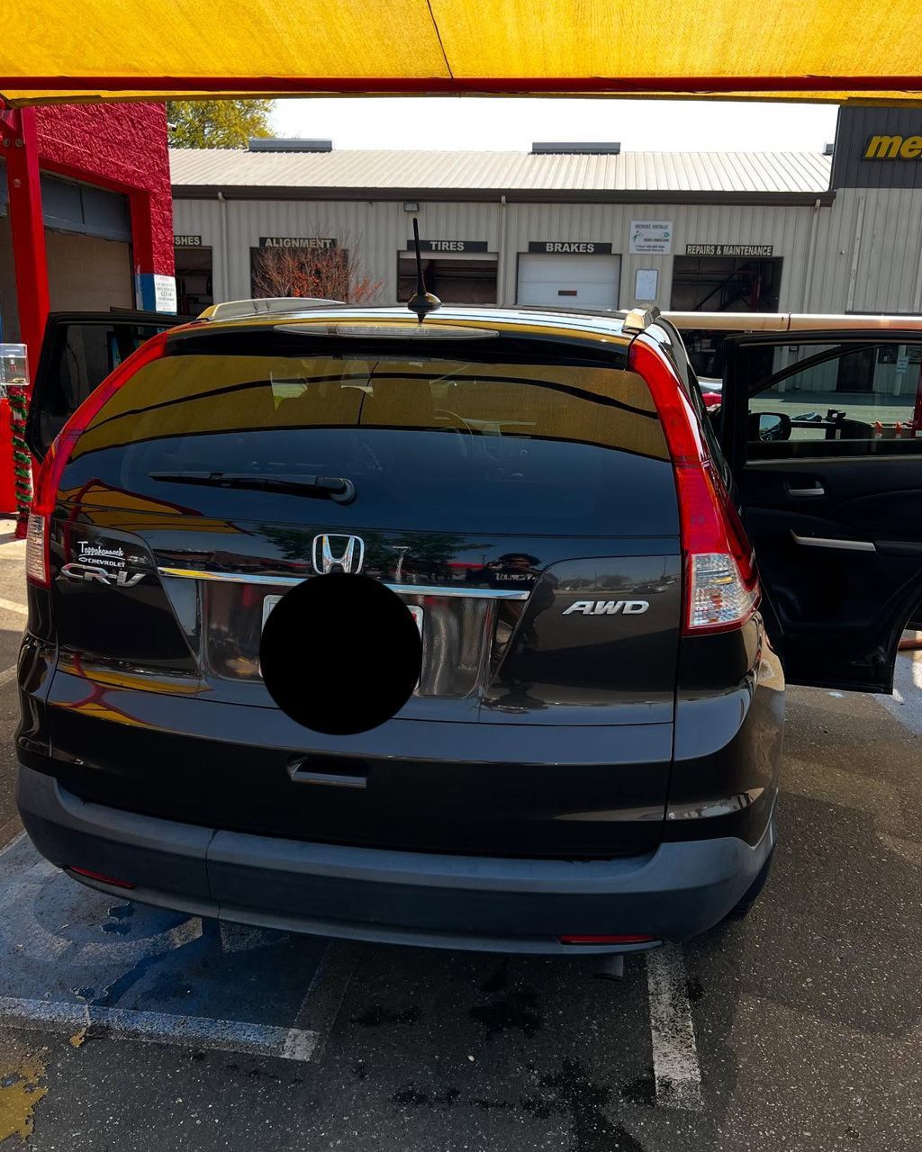 Black Honda CR-V at a carwash, rear view. Open doors. Exterior setting, daytime.