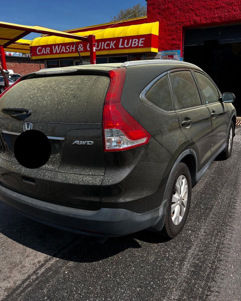 A dusty black Honda CR-V is in front of a car wash.