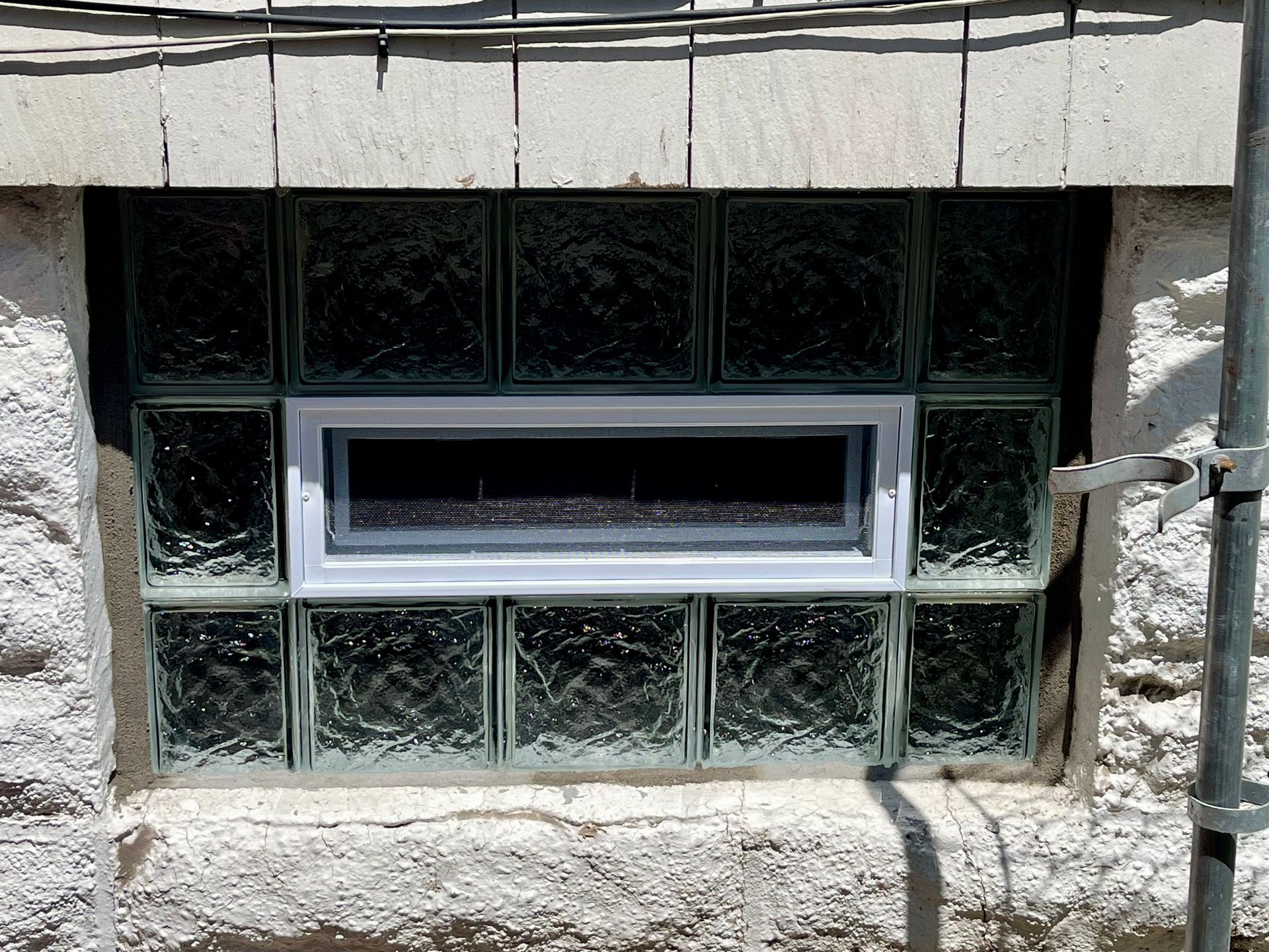 Basement window with rectangular glass block surround and a rectangular central window.