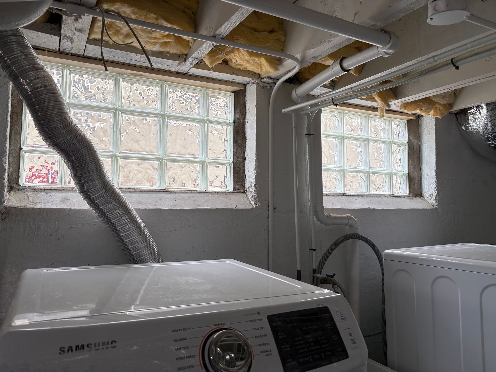 Laundry room with washing machine, dryer, and glass block windows.