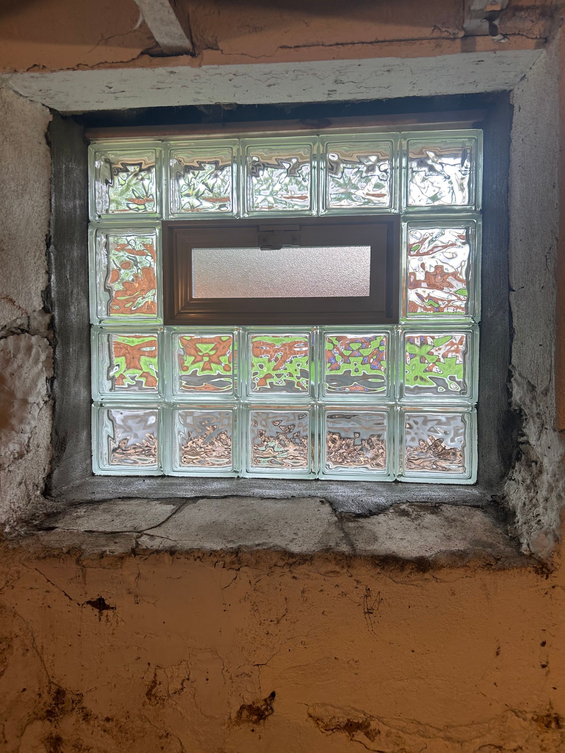 Glass block window in a concrete wall with a smaller, central frosted window.