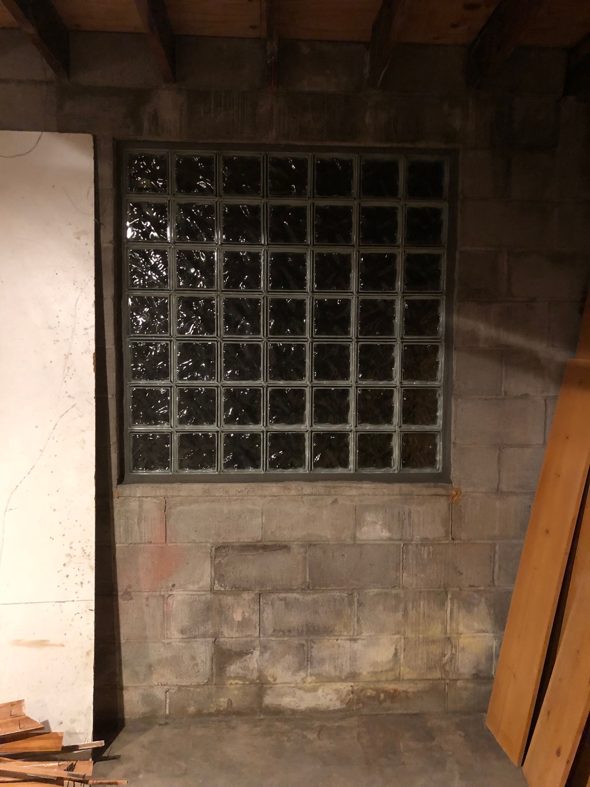 Window made of glass blocks in a basement wall; concrete blocks below; unfinished.
