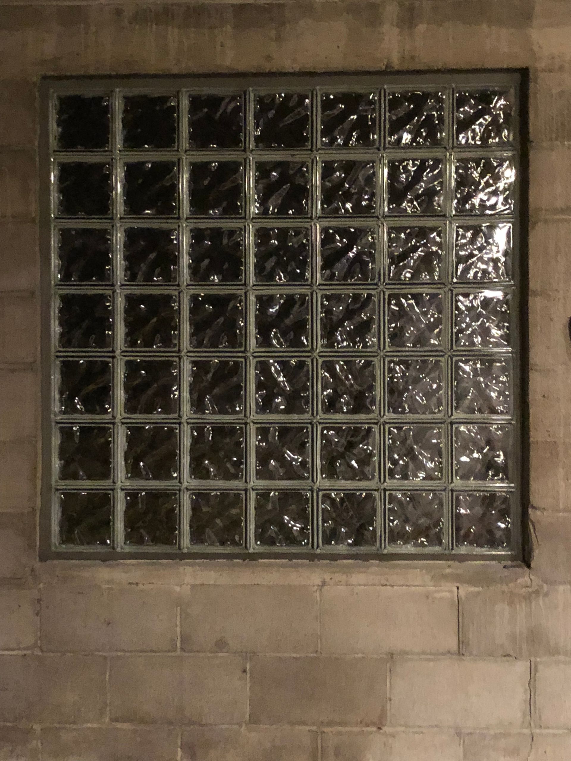 Glass block window set into a concrete block wall.